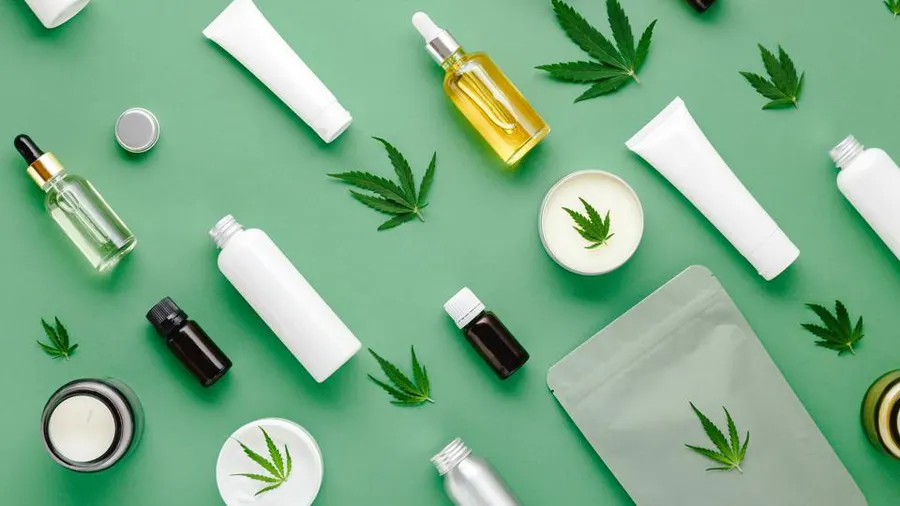 A flat lay of botanical skincare bottles, creams, and oils on green
